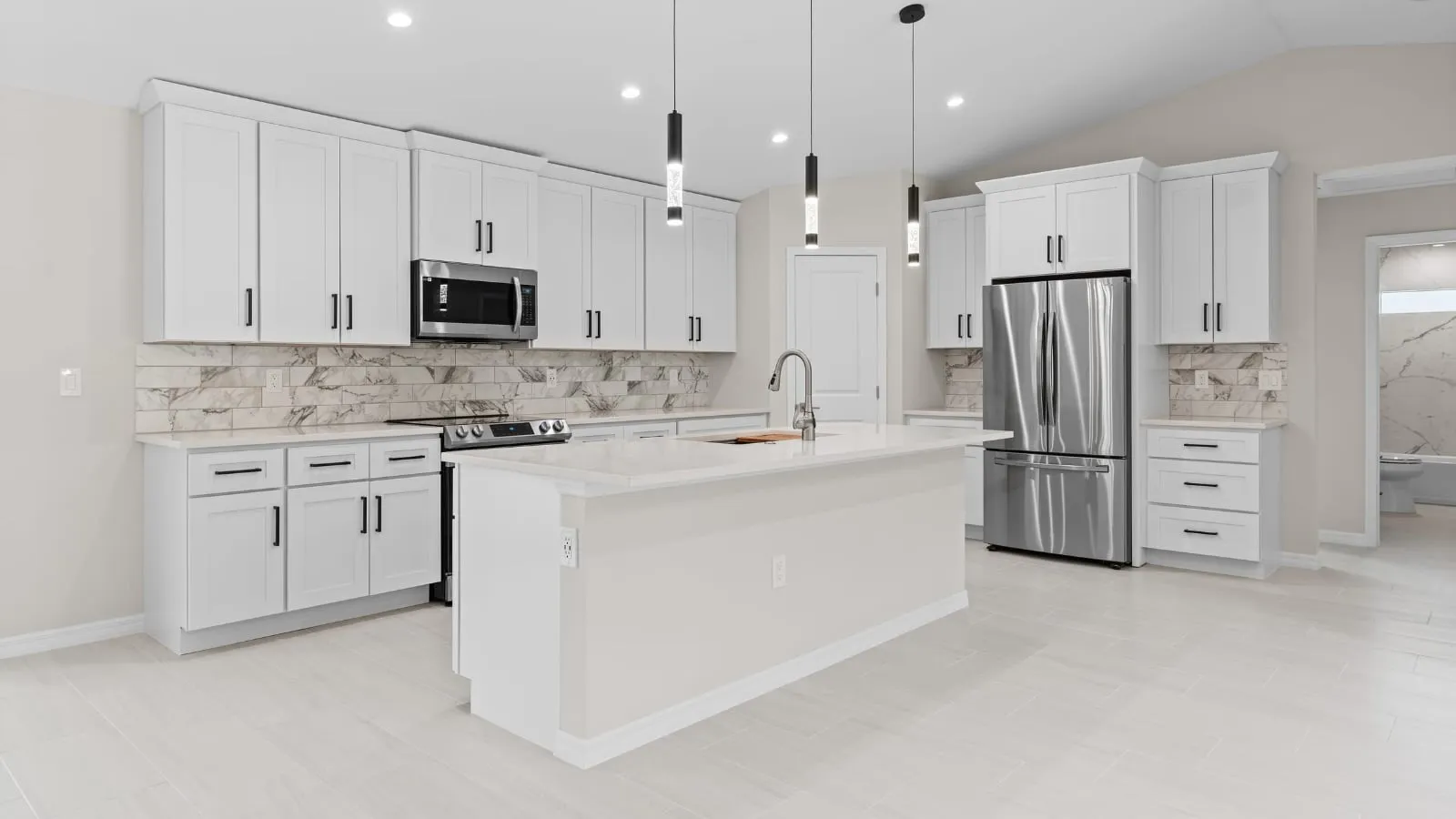 White shaker kitchen with an Absolute White quartz island and perimeter countertops, black pendant lights, a marble look tile backsplash and a stainless refrigerator