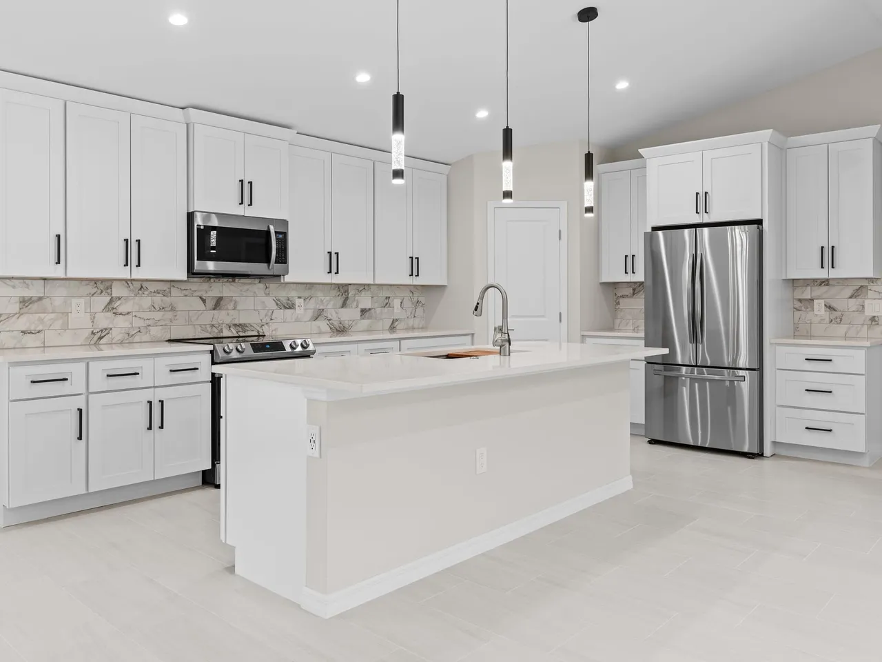 White shaker kitchen with an Absolute White quartz island and perimeter countertops, black pendant lights, a marble look tile backsplash and a stainless refrigerator